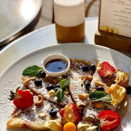 4 kleine Pfannkuchen Ahornsirup Puderzucker Obst geröstete Cashewkerne frische Minze zum Start in den Tag