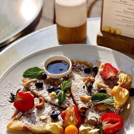 4 kleine Pfannkuchen Ahornsirup Puderzucker Obst geröstete Cashewkerne frische Minze zum Start in den Tag