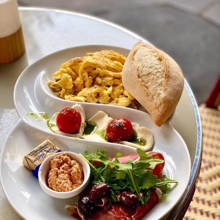 Rührei zum Frühstück mit Ricotta und Schinken sowie Brötchen