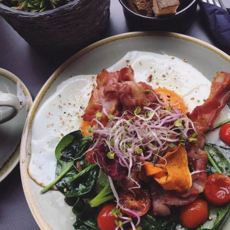 Zwei Spiegeleier mit Spinat und Bacon im Deer zum Frühstück